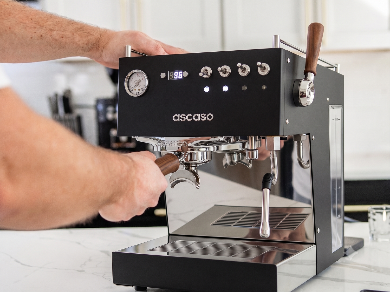 Person using an Ascaso espresso machine on a kitchen counter.