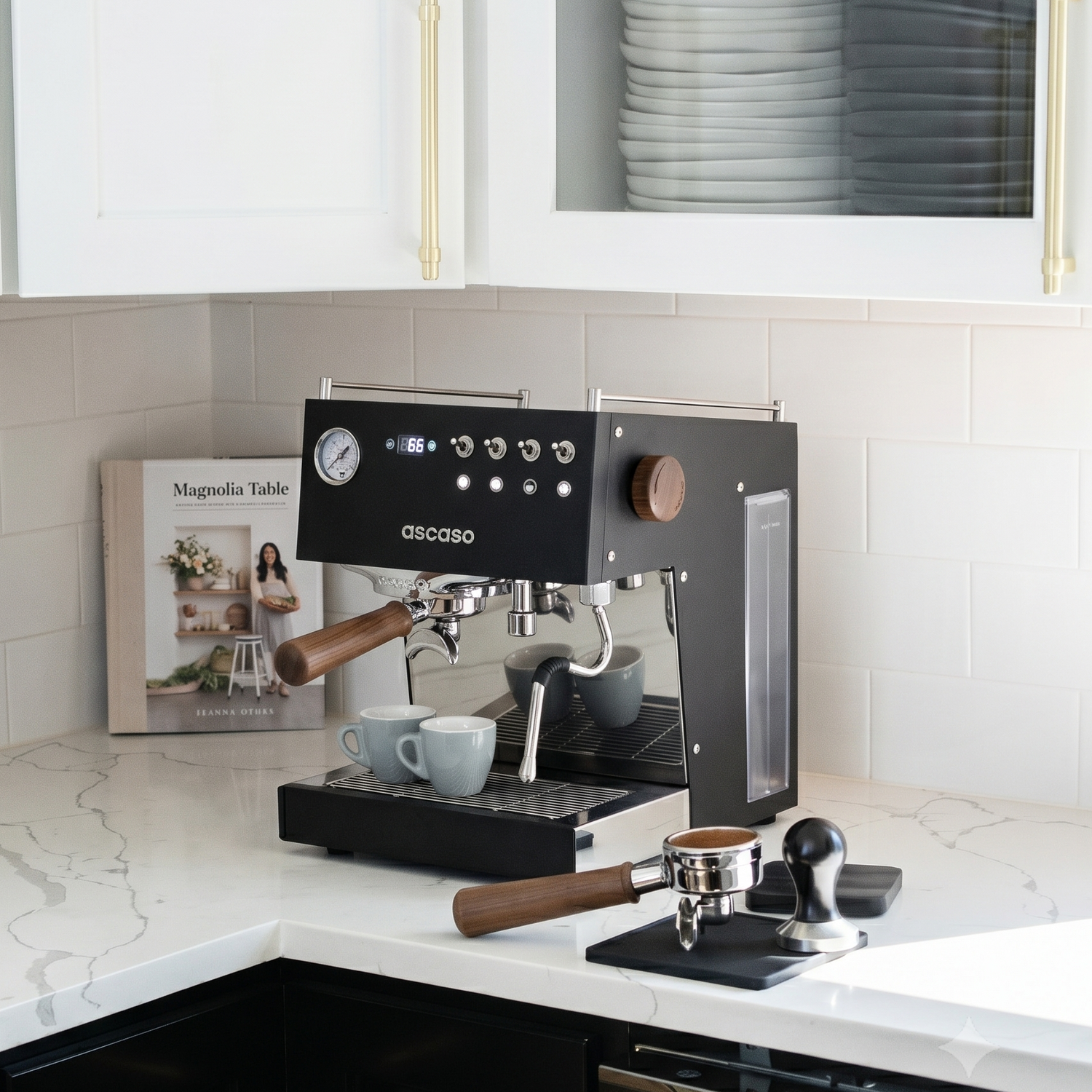 Black Ascaso espresso machine on a kitchen counter with a magazine and coffee cups.